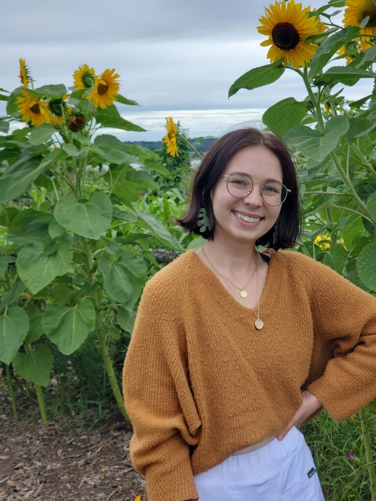 Janae smiling in front of sunflowers